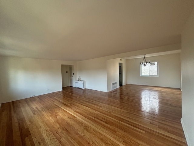 unfurnished living room featuring an inviting chandelier and hardwood / wood-style flooring