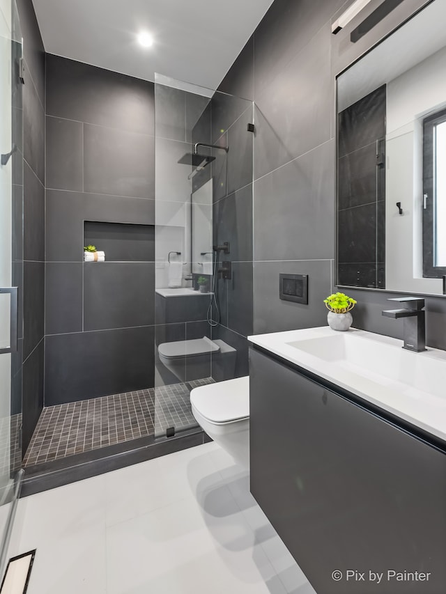 bathroom featuring toilet, vanity, a tile shower, and tile walls