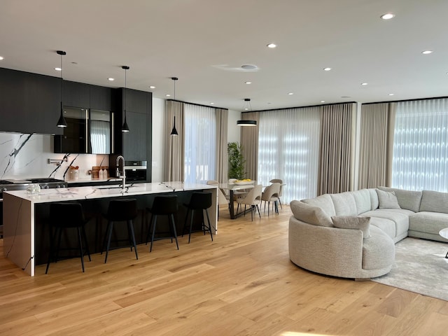 living room with sink, light hardwood / wood-style flooring, and plenty of natural light