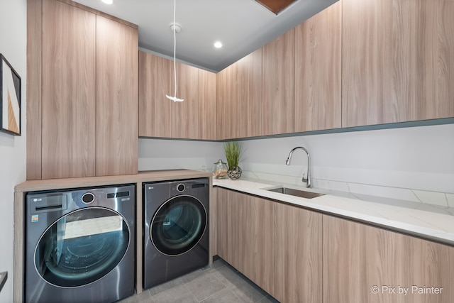 laundry room with sink, light tile patterned flooring, washing machine and clothes dryer, and cabinets