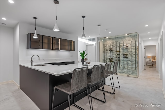 kitchen with dark brown cabinets, sink, decorative light fixtures, and a kitchen breakfast bar