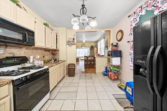 kitchen featuring tasteful backsplash, hanging light fixtures, a chandelier, light tile patterned flooring, and black appliances