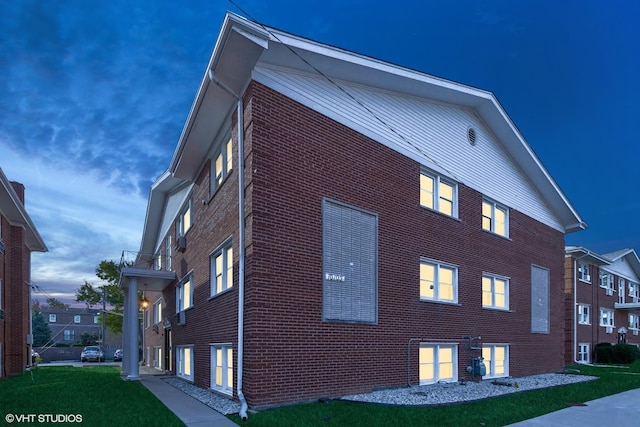 property exterior at dusk with a yard and a balcony