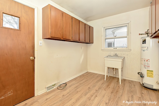 laundry room featuring cabinets, gas water heater, and light wood-type flooring