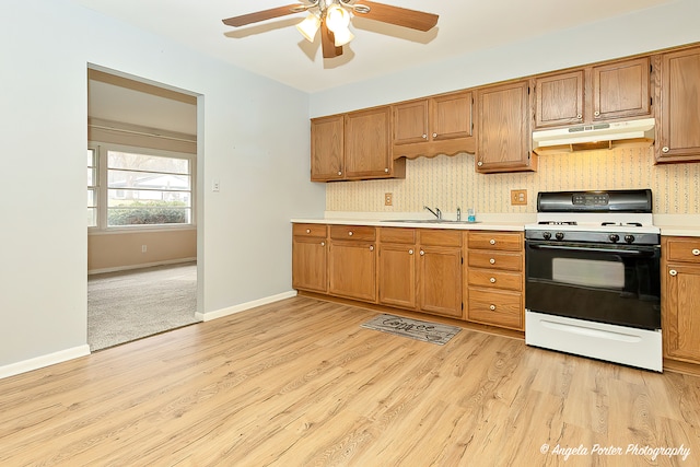 kitchen with ceiling fan, white gas stove, light wood-type flooring, and sink