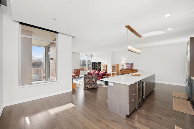 kitchen featuring dark hardwood / wood-style floors, a center island, hanging light fixtures, and beverage cooler