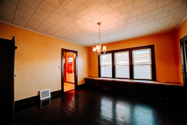 spare room featuring wood-type flooring, a notable chandelier, and crown molding