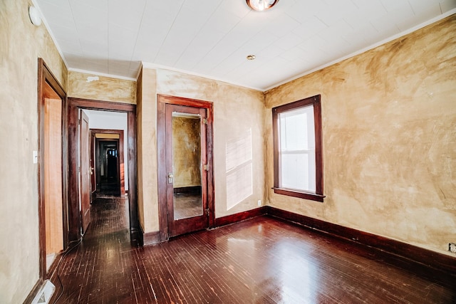 empty room featuring ornamental molding and dark hardwood / wood-style flooring