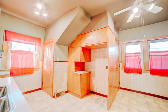 bathroom with ceiling fan, lofted ceiling, sink, and tile walls