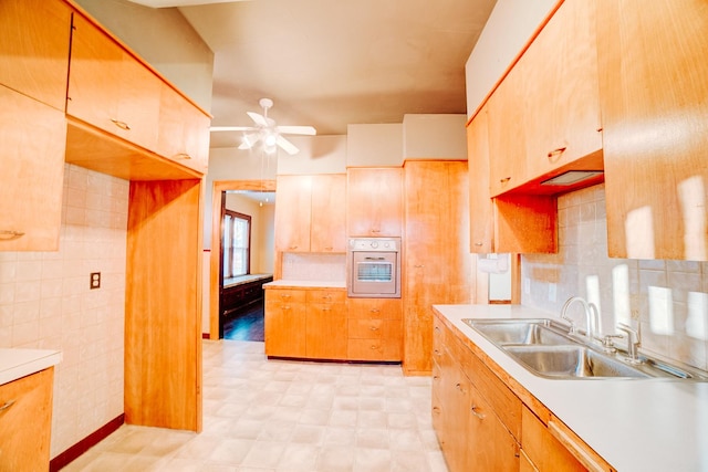 kitchen featuring sink, decorative backsplash, ceiling fan, and white oven