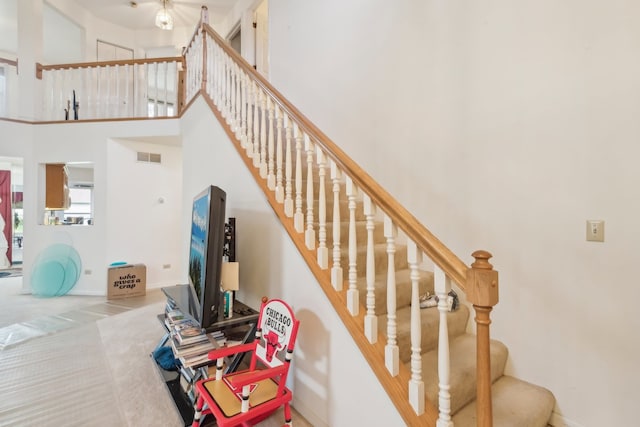 stairs with carpet floors and a high ceiling