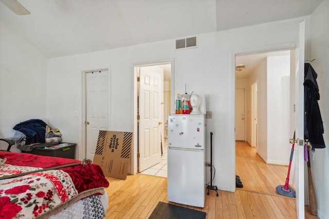 bedroom with light hardwood / wood-style floors, white refrigerator, and ceiling fan