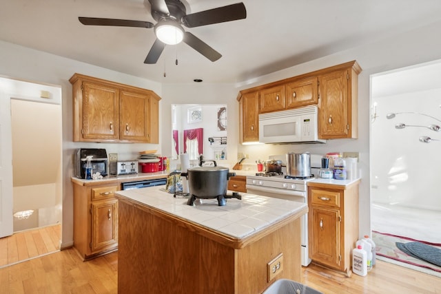 kitchen with white appliances, tile countertops, light hardwood / wood-style flooring, and a kitchen island