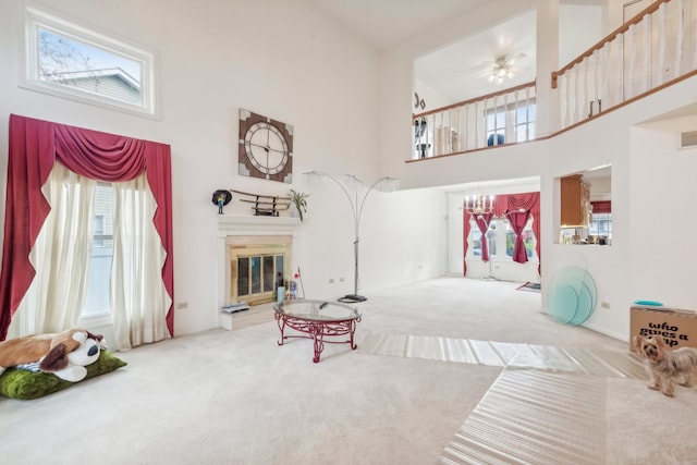 interior space with a high ceiling, carpet floors, and ceiling fan with notable chandelier