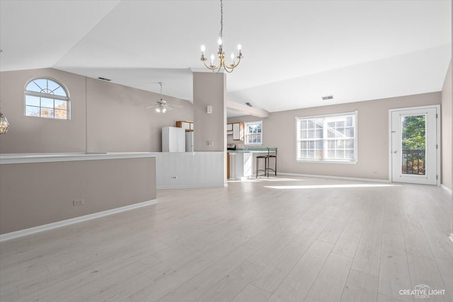 unfurnished living room with a healthy amount of sunlight, light wood-type flooring, and vaulted ceiling