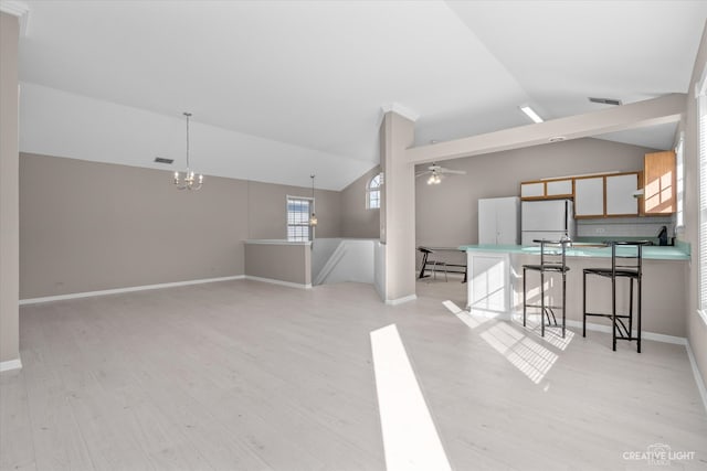 interior space with lofted ceiling, ceiling fan with notable chandelier, and light wood-type flooring