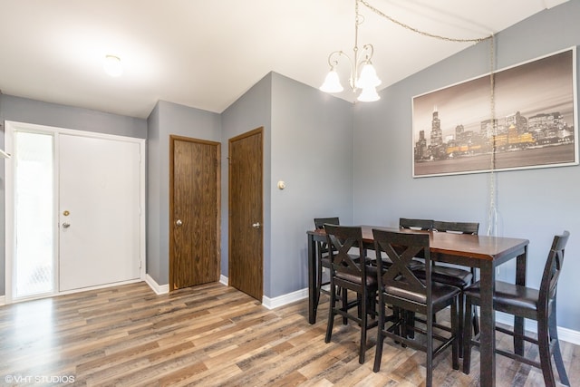 dining space featuring a notable chandelier, hardwood / wood-style flooring, plenty of natural light, and vaulted ceiling