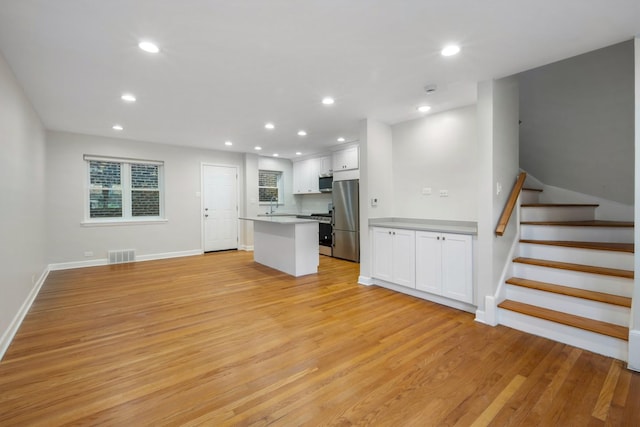 unfurnished living room with sink and light hardwood / wood-style floors