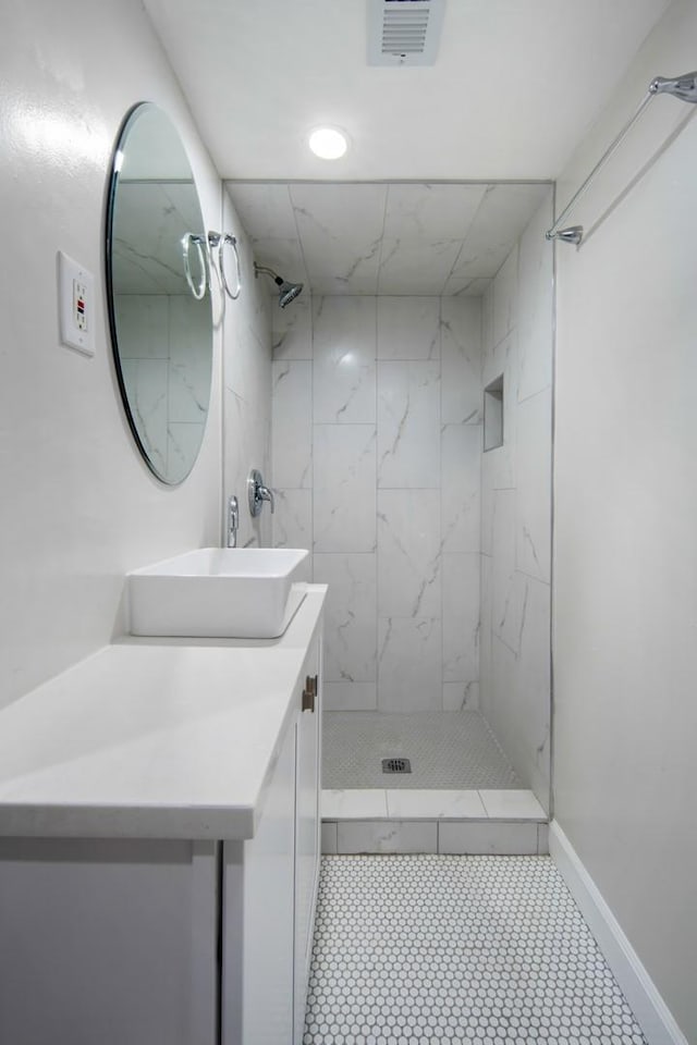 bathroom with a tile shower and vanity