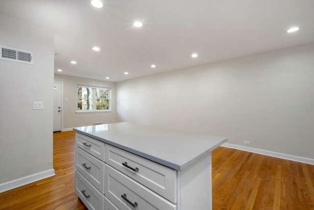 kitchen with white cabinetry, light hardwood / wood-style floors, and a kitchen island