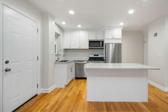 kitchen featuring white cabinetry, sink, stainless steel appliances, and a center island