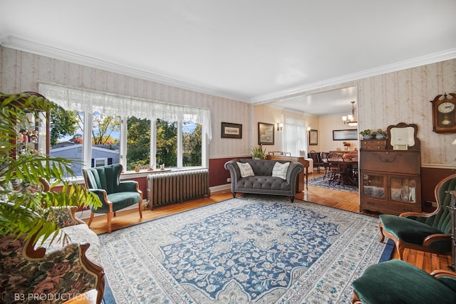 living room with radiator, crown molding, hardwood / wood-style flooring, and a chandelier