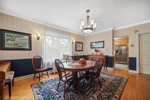 dining space featuring ornamental molding, a chandelier, and light wood-type flooring