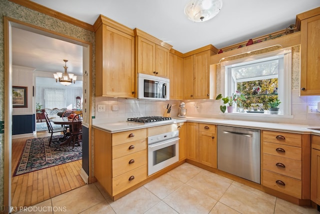 kitchen featuring tasteful backsplash, appliances with stainless steel finishes, light wood-type flooring, pendant lighting, and an inviting chandelier