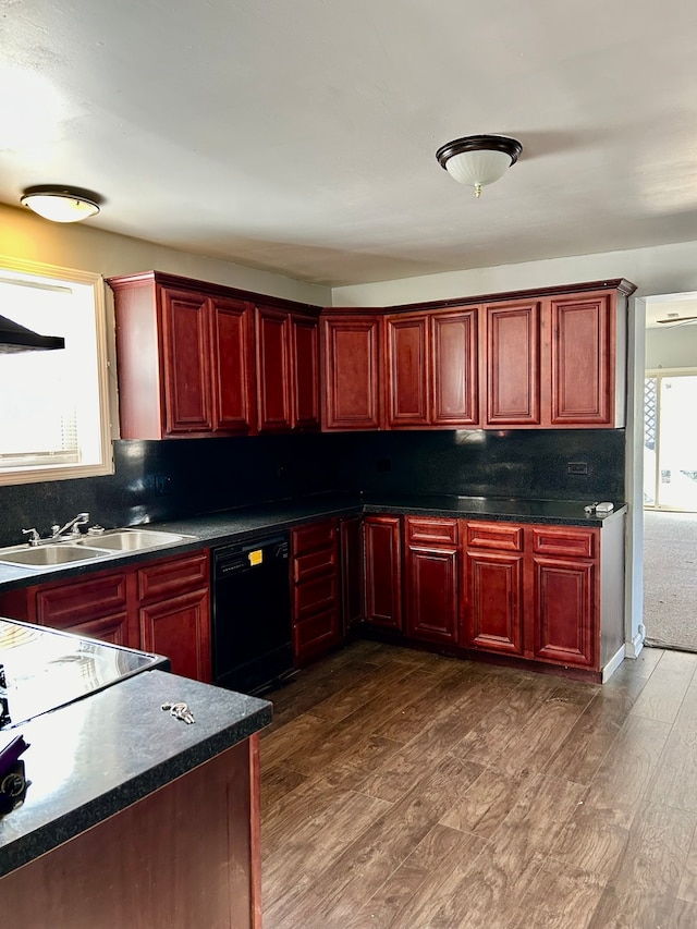 kitchen with reddish brown cabinets, dark countertops, black dishwasher, and a sink