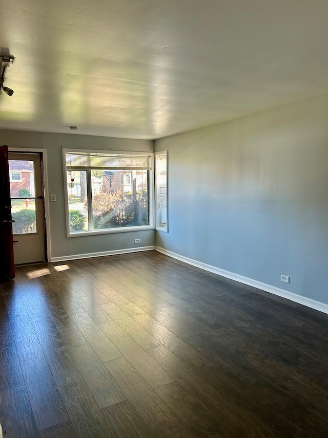 unfurnished room featuring baseboards and dark wood-type flooring