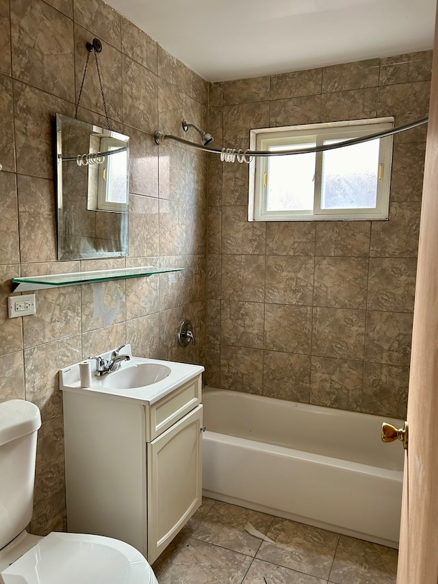 full bathroom with toilet, tile patterned flooring, tiled shower / bath, tile walls, and vanity