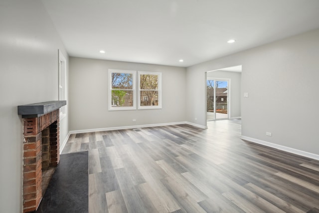 unfurnished living room with a brick fireplace and hardwood / wood-style flooring