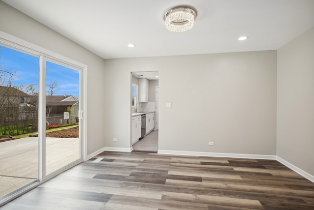 unfurnished room featuring hardwood / wood-style floors, a chandelier, and sink