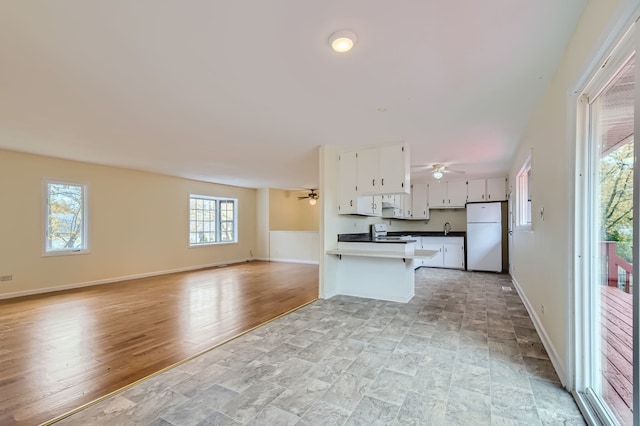 kitchen featuring plenty of natural light, kitchen peninsula, white appliances, and white cabinets