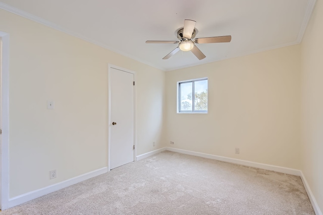 empty room featuring ceiling fan, light carpet, and ornamental molding