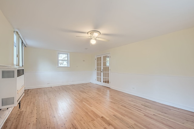 empty room with ceiling fan, heating unit, light hardwood / wood-style flooring, and french doors