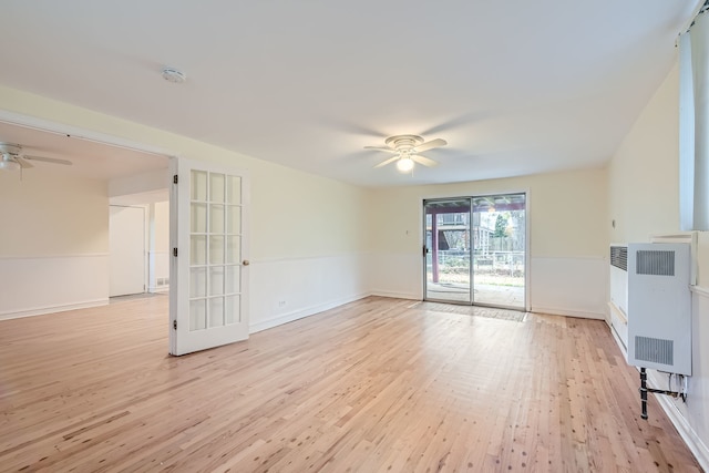 unfurnished living room with ceiling fan, heating unit, and light hardwood / wood-style floors