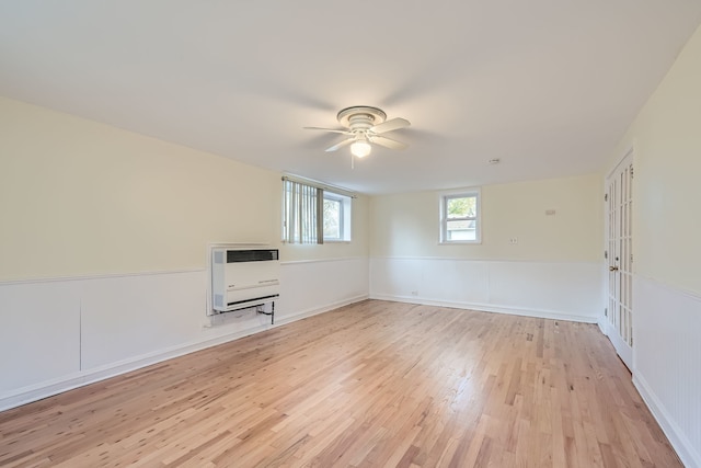 empty room featuring ceiling fan, heating unit, light hardwood / wood-style flooring, and french doors