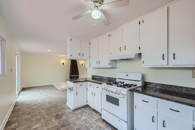 kitchen with white cabinets, white range with gas stovetop, dark stone counters, and ceiling fan