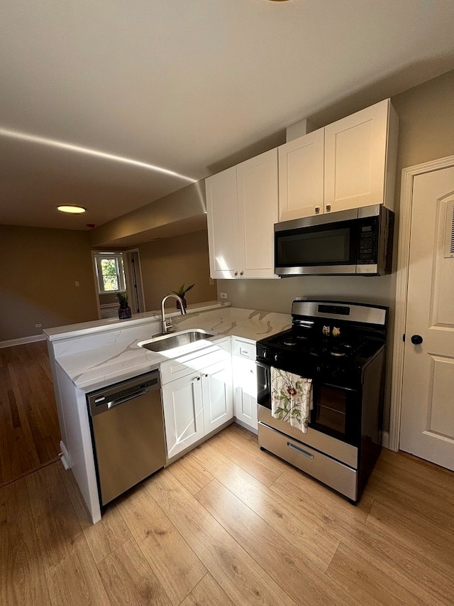 kitchen featuring kitchen peninsula, white cabinets, stainless steel appliances, and sink