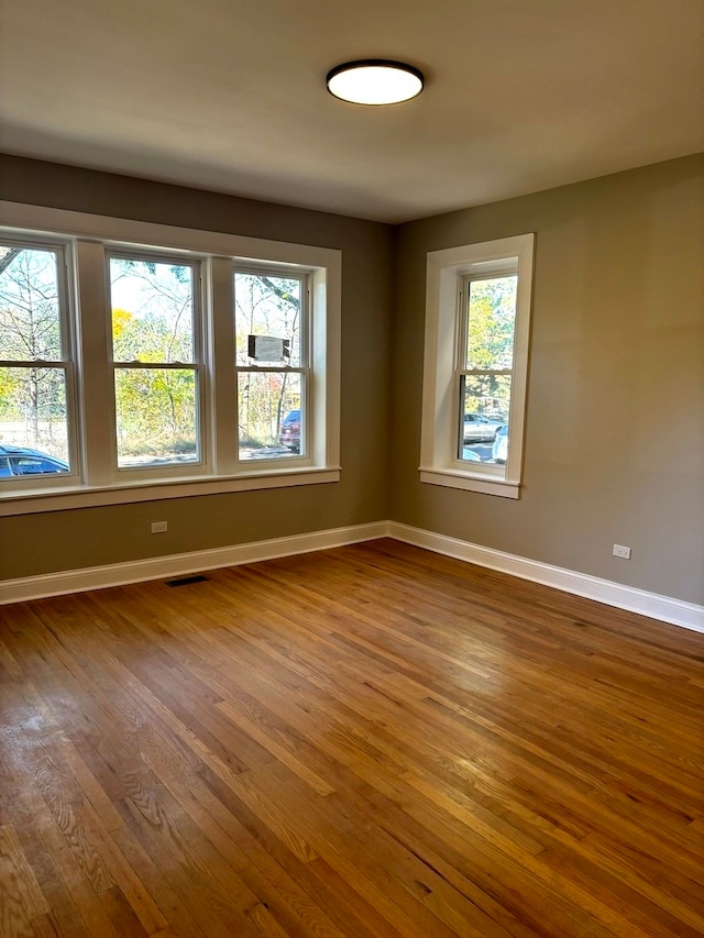 unfurnished room with a wealth of natural light and hardwood / wood-style floors