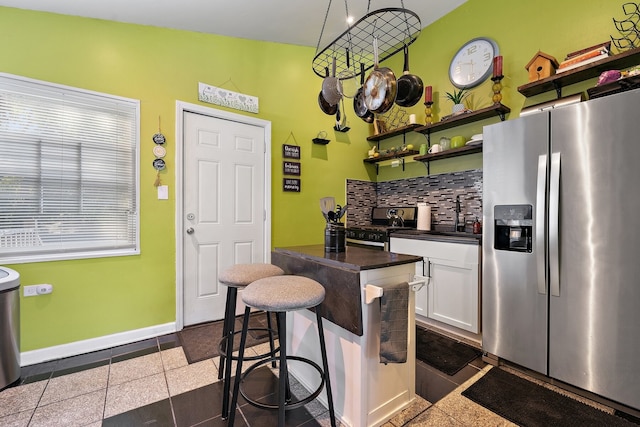 kitchen featuring sink, backsplash, white cabinetry, stainless steel appliances, and a breakfast bar