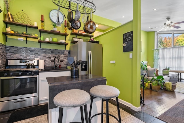 kitchen featuring decorative backsplash, ceiling fan, dark hardwood / wood-style flooring, white cabinetry, and stainless steel appliances