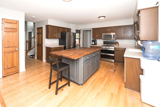 kitchen featuring appliances with stainless steel finishes, sink, a kitchen island, light hardwood / wood-style floors, and wooden counters