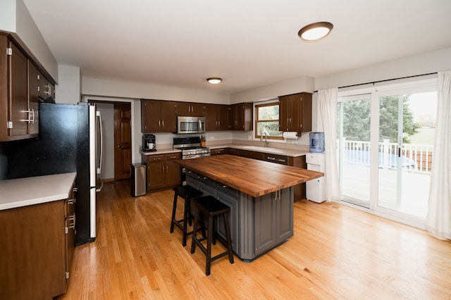 kitchen featuring a breakfast bar, butcher block countertops, stainless steel appliances, and light wood-type flooring