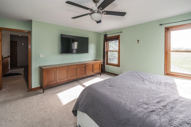 bedroom featuring multiple windows, light colored carpet, and ceiling fan