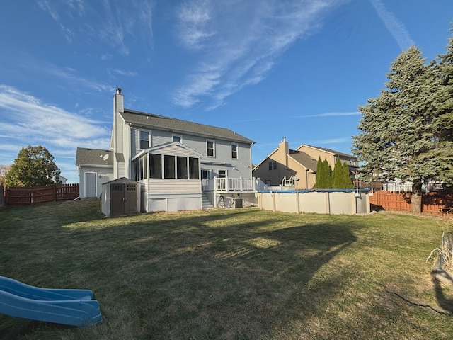 rear view of house featuring a fenced in pool, a lawn, and a sunroom