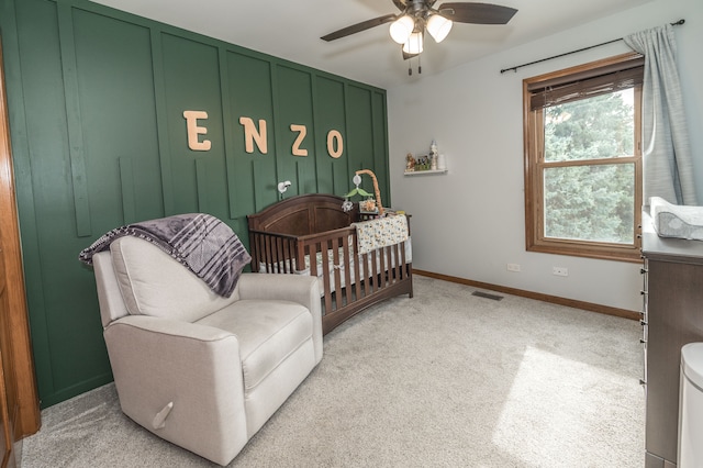 bedroom with ceiling fan, light carpet, and a crib