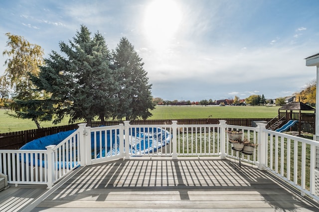 wooden deck featuring a playground and a lawn