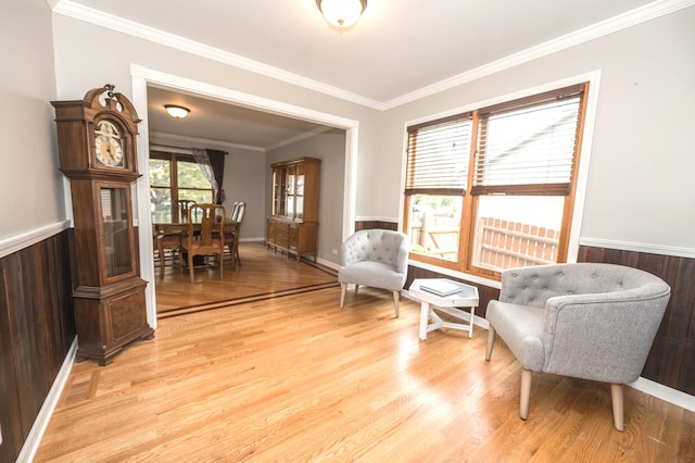 living area featuring crown molding, wood walls, and light wood-type flooring